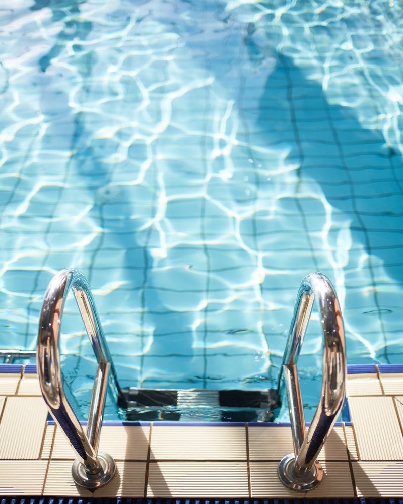 Modern swimming-pool with clean and transparent water and steel railings