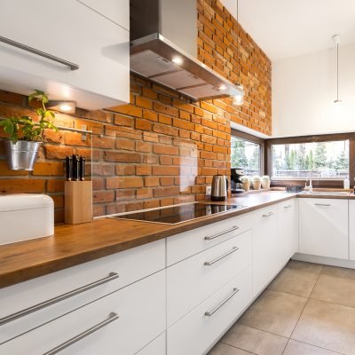 Brick wall in spacious modern designed white kitchen with marble floor